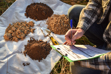Closeup male agronomist preparing soil samples for laboratory analysis, writing in information...