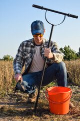 Male agronomist taking sample with soil probe sampler at agricultural field at sunrise. Farmer using drilling tool for soil sampling at morning outdoors. Environment research, soil certification