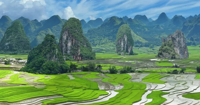Animated aerial landscape, flying over rice fields in China, approaching a karst mountain range.