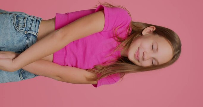Cute embarrassed shy child girl blogger showing embarrassment gesture by forefingers, shooting vertical video