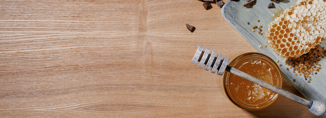 Honey background. Sweet honey in a glass jar and a honey spoon on a wooden table. Banner. Copy space for your text