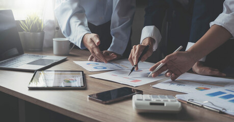 Closeup of businesspeople hands pointing a pie chart together on the paperwork