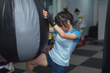 A mixed martial arts novice athlete executes a knee strike or a muay khao with a teardrop punching...