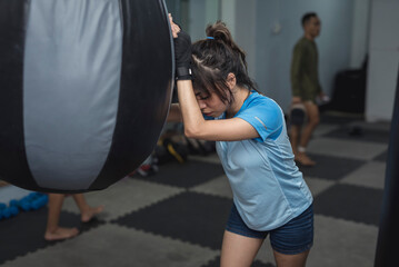 A female athlete rests her head on a teardrop punching bag inside the gym as she trains for the MMA tournament.
