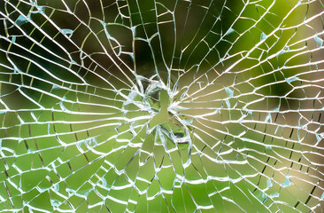 Shallow focus of a shattered double glazed window caused by a stone being flicked up by a garden mower, producing a hole and breaking the glass.