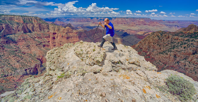 A hiker on the edge of a cliff along Buggeln Hill Trail halfway between Grandview Point and the Sinking Ship at Grand Canyon Arizona.