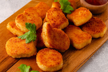 Fried crispy chicken nuggets on a wooden serving board.