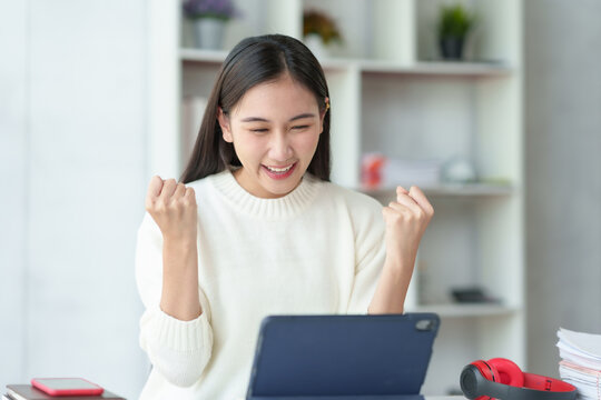 Pretty young Asian businesswoman sitting on a laptop Glad that the work came out, achieved the desired goal and was happy and satisfied with the results..