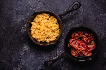 Cooked scrambled eggs and fried bacon in portion pans