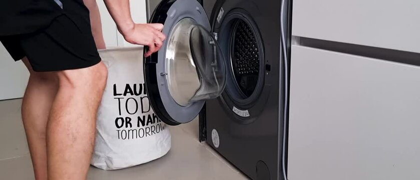 Slow motion footage of a laundry being loaded into the washing machine. Chores