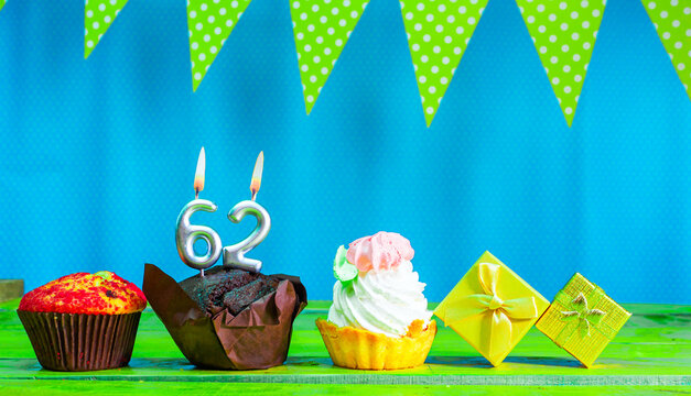 Happy birthday colorful background with decorations with festive garlands with pies and muffins and gift boxes with copy space. Beautiful happy birthday background with number 62 candles
