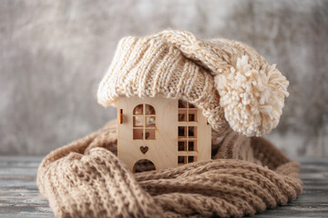 Figure of wooden house and warm clothes on table . Concept of heating season