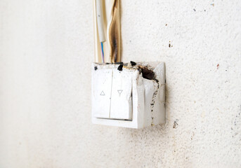 Melted light switch with fire damage, close up. Light regulator mounted on wall caught on fire....