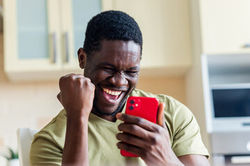happy afro american man winner excited by mobile app with joy