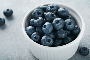 Blueberry. White bowl of fresh blueberries on grey stone background table. Tasty ripe blueberries. Place for text. Food background. Top view.