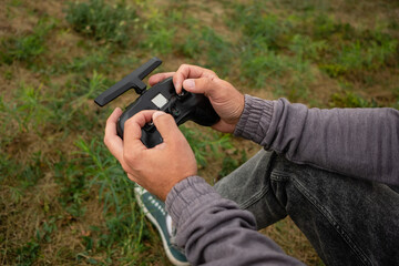 Man hands remote control sticks of and fly on FPV drone at drone racing competition.