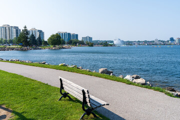 Centennial Park walking Path and wooden bench. Downtown Barrie curves around the shore of...