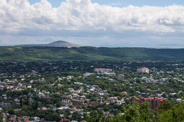 Obraz premium Panoramic top view of the city of Pyatigorsk Stavropol territory in a green valley and a mountain on the horizon on a sunny summer day and a space to copy