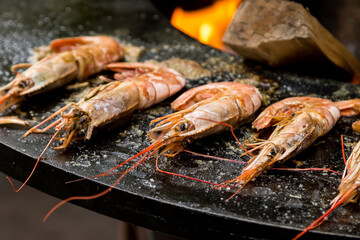 Grilled large shrimps on grill pan with fire in the background