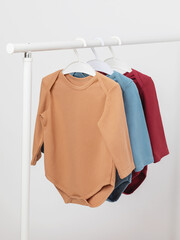 Baby overalls with long sleeves on a hanger, baby bodysuits in three colors