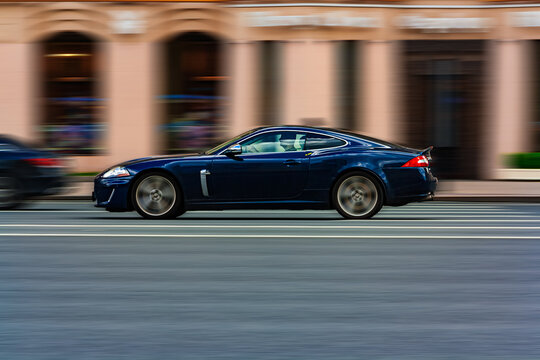 Jaguar XKR rushing on the city road. Blue Jaguar XKR X150 coupe car moving on the street