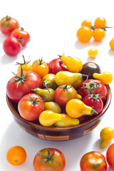 Organic red and yellow tomatoes in a bowl on a white background. Freshly picked heirloom tomatoes. Healthy eating concept.