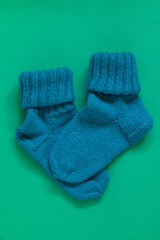 Two knitted wool turquoise socks for winter on a green background. Top view.