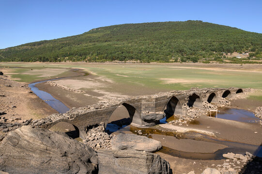 Close-up of the ruins of the Roman bridge of Vinuesa, Soria Spain. Behind the plain and the grass that grows at the bottom of the dry and empty swamp. only the original river that fed the dam is visib