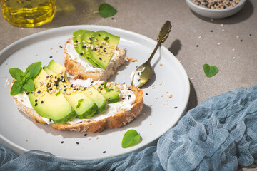 Healthy toast with avocado cream cheese and wheat bread on a plate. Delicious snacks and avocado sandwiches. Food composition, tasty Italian meal.