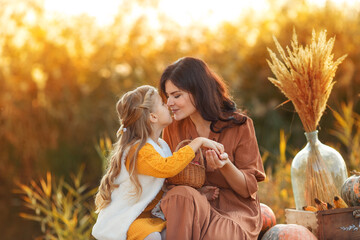 Mom and daughter at the sunset. Happy young mother hugging her daughter on sunshine warm autumn...