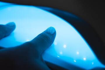Manicurist master is covering painting client's nails top coat shellac, hands closeup. One hand...