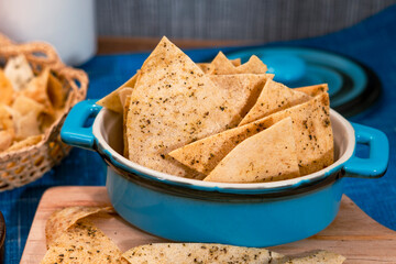 Blue ceramic bowl with handles containing corn chips. Totopos made with fried corn tortillas. Fries...