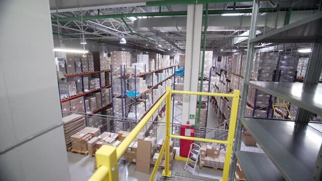 View inside of a warehouse with many rows of metal shelves and goods. Creative. Modern storehouse with cardbox boxes.