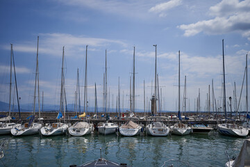 Fototapeta premium Desenzano del Garda, Italy - July 12, 2022 - yachts and boats docked at the port on Lake Garda on a sunny summer morning