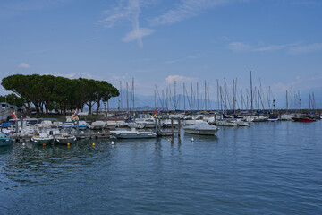 Fototapeta na wymiar Desenzano del Garda, Italy - July 12, 2022 - yachts and boats docked at the port on Lake Garda on a sunny summer morning