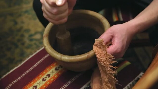 A man hands grind a poppy holding a wooden pestle and a old clay mortar - rustic style. Preparation for cooking traditional Ukrainian dish - Christmas Kutia. Festive porridge for the whole family