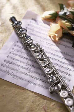 Close-up of a flute on music sheets near roses