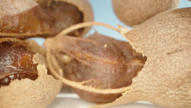 Tamarind fruits, in the shell and without, on the table. Dolly slider extreme close-up.