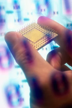 Binary code superimposed over a person's hand holding a computer chip