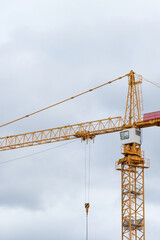 Yellow building constraction tower crane against gray sky