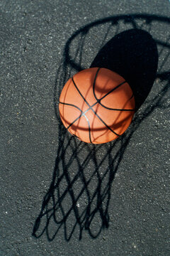 Close-up of a basketball resting on the shadow of a basketball hoop