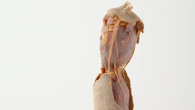The tamarind fruit is half peeled, rotates on a white background, extreme close-up.