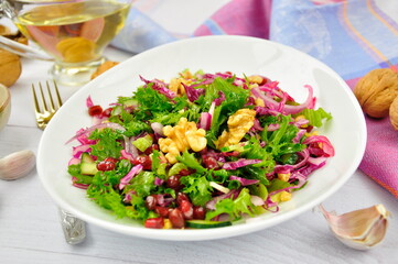 Healthy vegetarian Salad with pomegranate, walnuts and lettuce leaves.
