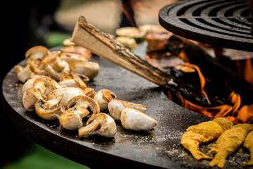 View of grilled mushrooms on an outdoor barbecue with flames, champignons