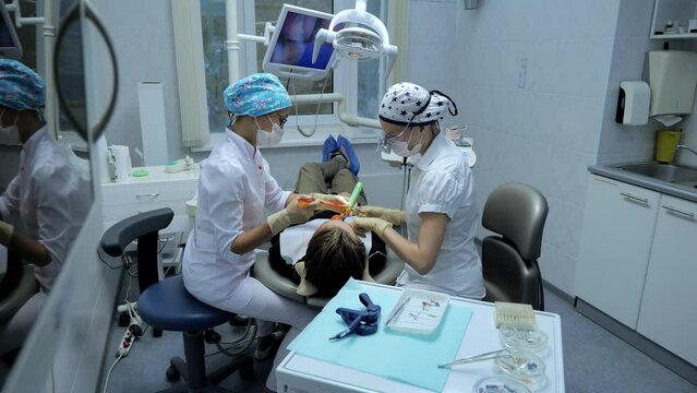 Female dentist treating a tooth to a male patient in a dental chair