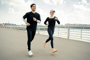 A young couple do sports, train outside, have a healthy lifestyle. Fitness watch on hand.