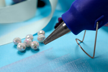 Hot glue gun and handicraft materials on light blue table, closeup