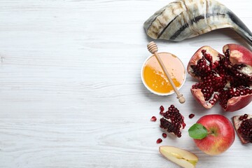 Honey, pomegranate, apples and shofar on white wooden table, flat lay with space for text. Rosh Hashana holiday
