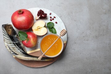 Honey, pomegranate, apples and shofar on grey table, top view. Rosh Hashana holiday
