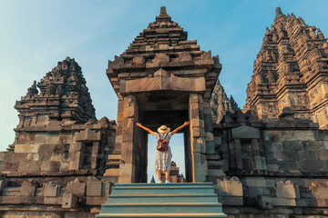 Indonesia, Prambanan- young girl with hat standing with open arms under the door Prambanan temple...